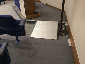 A photograph of a ramp placed over the step up to the lecturn in the Lecture Theatre at Burlington House